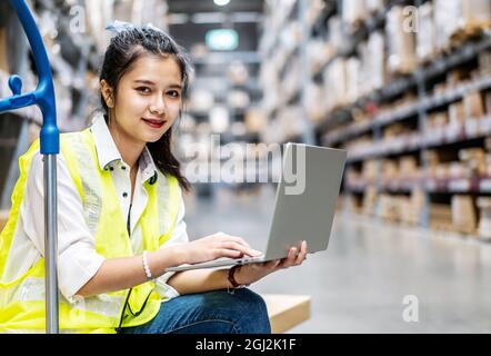 Young female warehouse workers working on laptop in a large warehouse Stock Photo