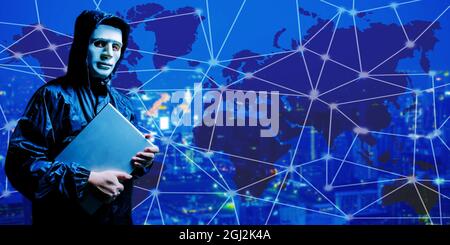 Anonymous computer hacker holds a laptop tight in his hands on on digital world map city background Stock Photo