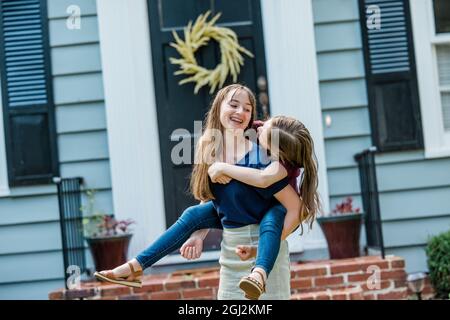 A father holding his 10 year old daughter piggyback on his back while outside Stock Photo