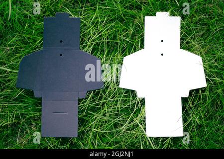 top view of two black and white empty unfolded box for accessories for sewing clothing tags on green grass, with copy space Stock Photo