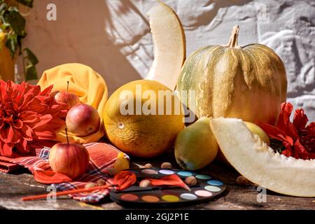 Autumn aesthetic fair: yellow fruits and vegetables and bright paints with a brush, pumpkin, pears, apple and melon. Thanksgiving Day concept. Autumn Stock Photo