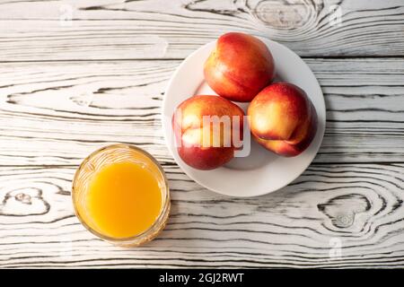 Peaches on a wooden table, nectarine, peach juice. Healthy light breakfast. Selective focus Stock Photo