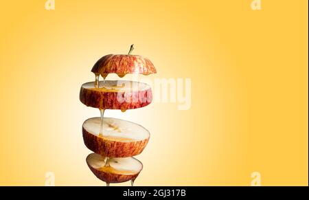 Fresh sliced Red apple and honey dripping in flying food with levitation reflection. Alternative sugar substitute, cold remedy and body strengthening, Stock Photo