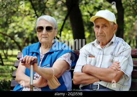 Elderly couple sitting on a bench. Old man and woman together, leisure in park, life in retirement Stock Photo