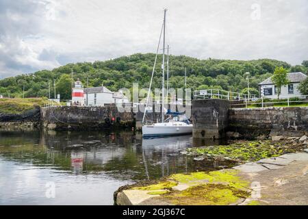 Boat emerging from  from the sea lock at the west end of the Crinan canal in Argyll and Bute, Scotland Stock Photo