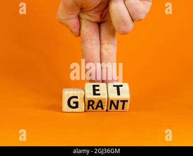 Get grant symbol. Businessman turns wooden cubes with concept words 'Get grant' on a beautiful orange background. Copy space. Business and get grant c Stock Photo