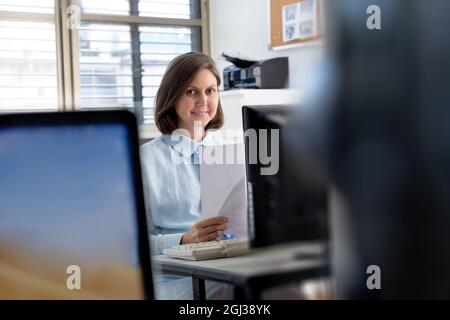 Young woman working in the office with documents near the computer Stock Photo