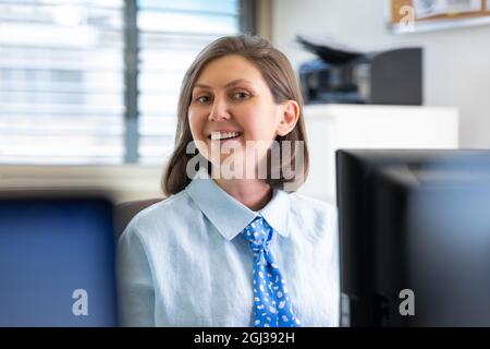 Young woman working in the office with documents near the computer. woman smiling Stock Photo