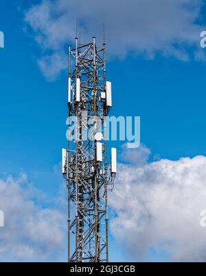Communications tower with antenna against a blue and cloudy sky Stock Photo