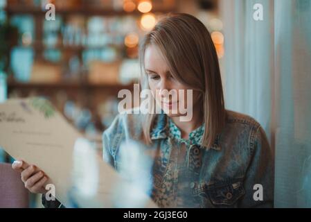 Woman is looking at menu in restaurant. Stock Photo