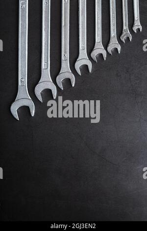 A set of wrenches on a textured black background in a row. Top view, free space Stock Photo