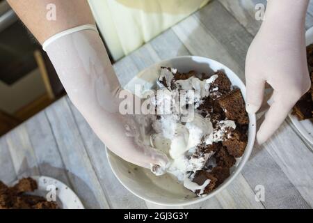 Cake making process. Female hands in culinary gloves form a chocolate cake with sour cream. Step by step recipe for chocolate cake. Series. Baking con Stock Photo