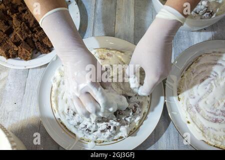 Cake making process. Female hands in culinary gloves form a chocolate cake with sour cream. Step by step recipe for chocolate cake. Series. Baking con Stock Photo