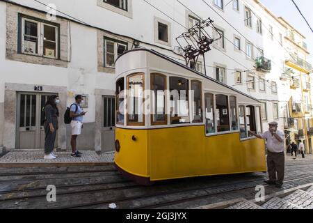 Lisbon, Portugal. 1st Sep, 2021. People are seen next to the Bica funicular, in Lisbon.The Bica funicular was inaugurated in 1892 as a link between ''Largo do Calhariz'' Square and ''Rua de Sao Paulo'' Street. It worked with the rack rail and water counterbalance system and later with steam. The funicular was then electrified in 1927 and classified as a national monument in 2002. (Credit Image: © Hugo Amaral/SOPA Images via ZUMA Press Wire) Stock Photo