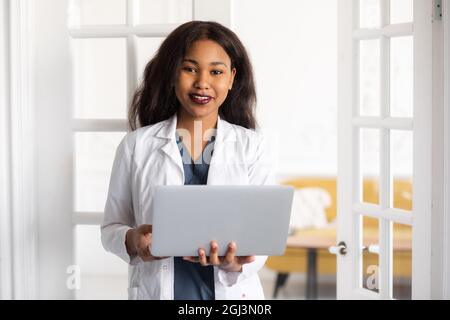 black skinned female medic smiling standing on a white background with papers in hand Stock Photo