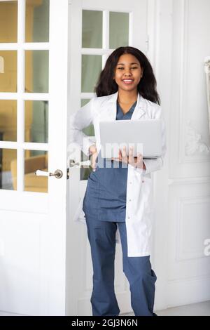 black skinned female medic smiling standing on a white background with papers in hand Stock Photo