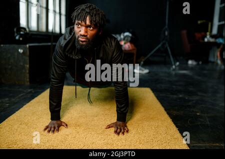 african american man doing push-ups in modern gym with large windows Stock Photo