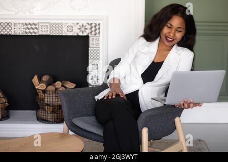 Handsome african american business woman in classic suit uses laptop and smiles while working in office Stock Photo
