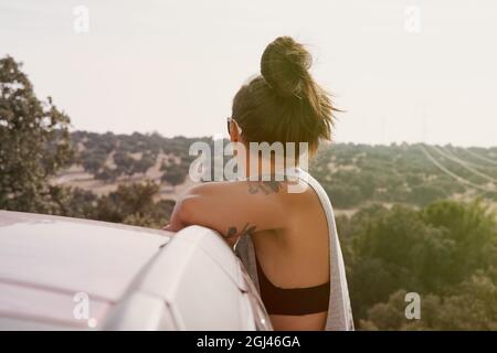 Rear view of a woman enjoying herself in a car in a field at sunset. Stock Photo