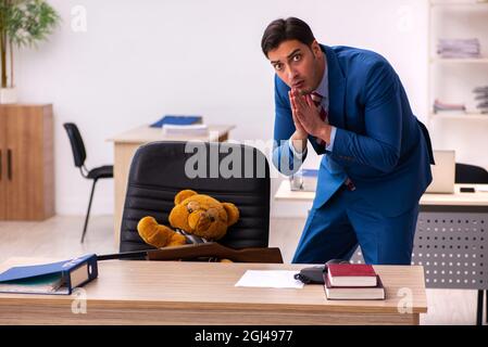 Young employee and his toy bear boss in funny concept Stock Photo