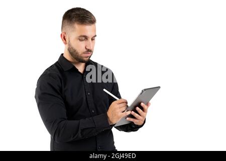 Young man with a black shirt taking notes on a grey tablet on a white background Stock Photo