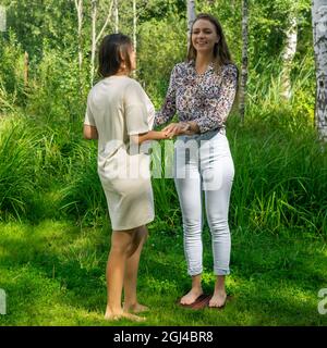 yoga coach helps a beginner to get on the sadhu board for the first time Stock Photo