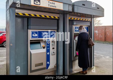 Woman buys a train ticket at a ticket machine at Midleton Railway Station, East Cork, Ireland. Stock Photo