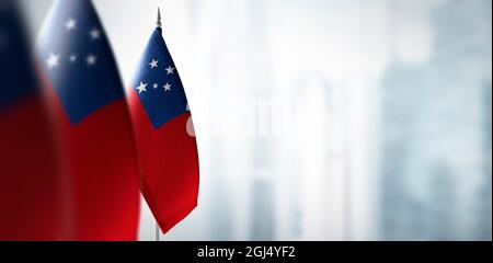 Small flags of Samoa on a blurry background of the city Stock Photo