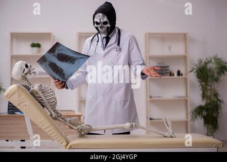 Devil doctor radiologist examining skeleton patient at the hospital Stock Photo