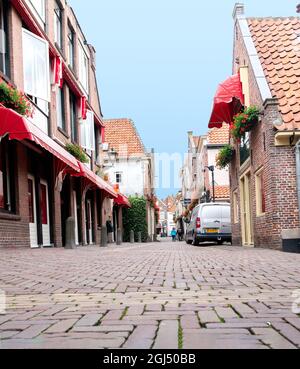 Alkmaar Netherlands - August 18 2012; Quiet picturesque cobbled street with brick and tile buildings with red canopies. Stock Photo