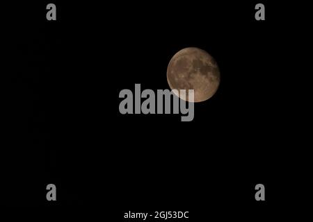 view on almost full Moon in dark sky Stock Photo