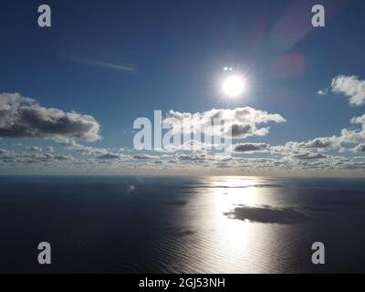 Abstract aerial nature summer ocean sunset sea and sky background. Small waves on clear water surface in motion blur with bokeh lights from sunrise Stock Photo