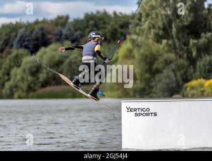 Wakeboarder making tricks. Low angle shot of man wakeboarding on a lake. Stock Photo