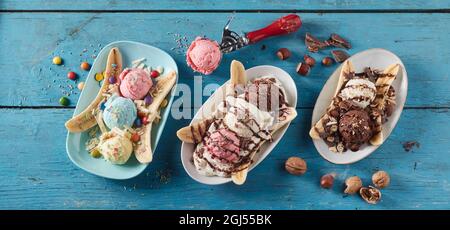 From above of row of plates with fresh banana slices and scoops of ice cream with different flavor served on blue wooden table Stock Photo