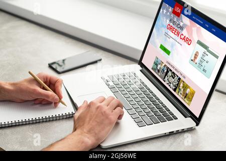 man with laptop with United States Permanent Resident Card website Stock Photo