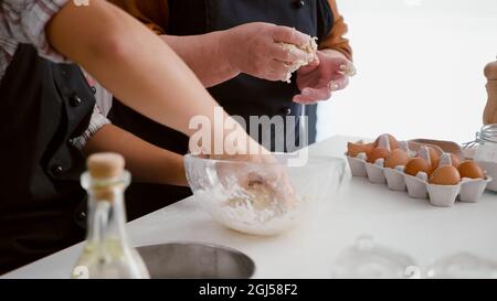 Closeup of granddaughter hands preparing homemade traditional cookies dough using flour during christmastime in xmas decorated kitchen. Family celebrating christmas making winter dessert Stock Photo