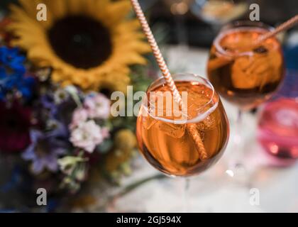 Orange cocktail drink with straws and sunflowers laid behind on table lots of bright vibrant colours at wedding reception Stock Photo