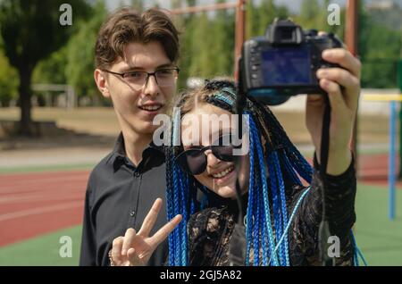 A happy young woman and a man taking selfies with a DSLR camera. Stock Photo