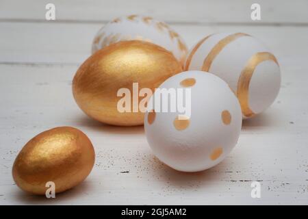 Golden Easter eggs on rustic old wooden background. Trendy Easter composition. Copy space for text. Minimal Easter concept. Stock Photo