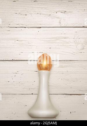 Golden Easter egg and white vase on rustic old wooden background. Trendy Easter flat lay composition. Copy space for text. Minimal Easter concept. Eas Stock Photo