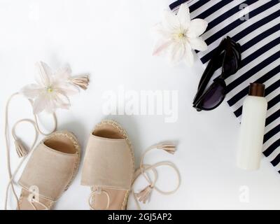Summer Flat lay. Summer sandals, white flowers, sunglasses and a white bottle.Top view. Creative background. Stock Photo