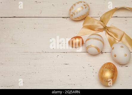 Golden Easter eggs on white rustic old wooden background. Trendy Easter flat lay composition. Copy space for text. Minimal Easter concept. Easter deco Stock Photo