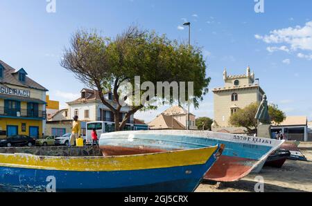 Traditional fishing boats on the beach of the harbor, landmark Torre de Belem in the background. City Mindelo, a seaport on the island Sao Vicente, Ca Stock Photo