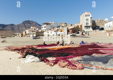 Fishermen are mending their colorful fishing nets on a beach near Sao Pedro. Island Sao Vicente, Cape Verde. Stock Photo