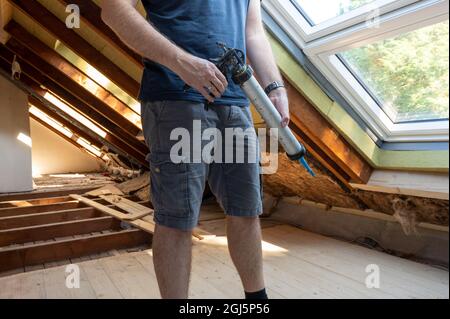 Craftsman caulking a new window in the attic. Stock Photo