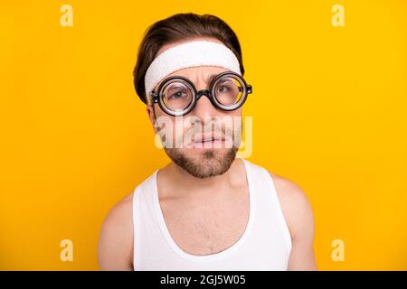 Portrait of attractive suspicious guy nerd sportsman looking at you spying isolated over bright yellow color background Stock Photo