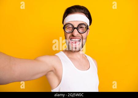 Self-portrait of attractive cheerful funny guy nerd sportsman grimacing having fun isolated over bright yellow color background Stock Photo