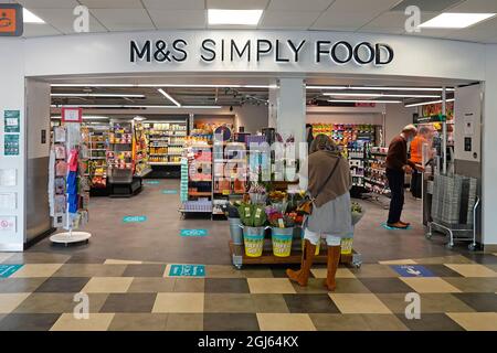 Marks & Spencer sign Simply Food shop a retail business in M5 motorway services shopping mall shoppers in Covid face masks West Midlands England UK Stock Photo