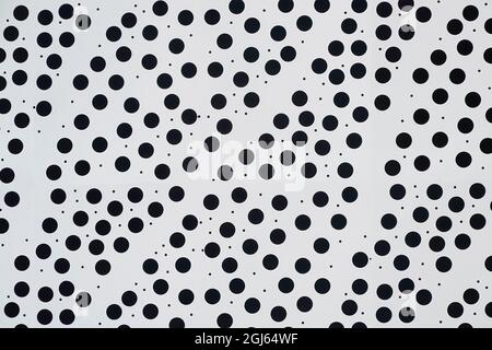 Abstract close up of spotty white background of building cladding panel regular size small circular black round dots & random tiny specks England UK Stock Photo