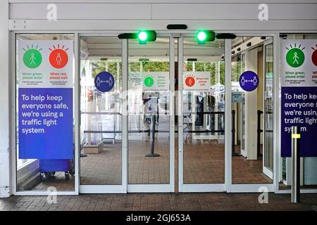 Tesco Supermarket store sliding door one way entrance traffic light system counts shoppers entering avoiding crowding in Covid 19 Coronavirus pandemic Stock Photo